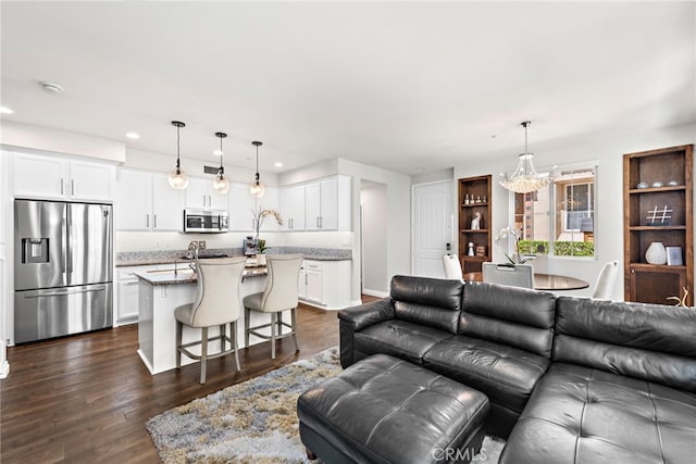 living room with recessed lighting, dark wood finished floors, and a notable chandelier