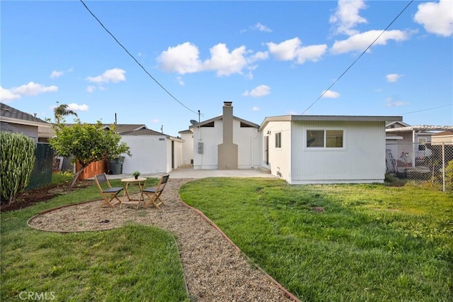 back of property with a yard, a patio, and fence