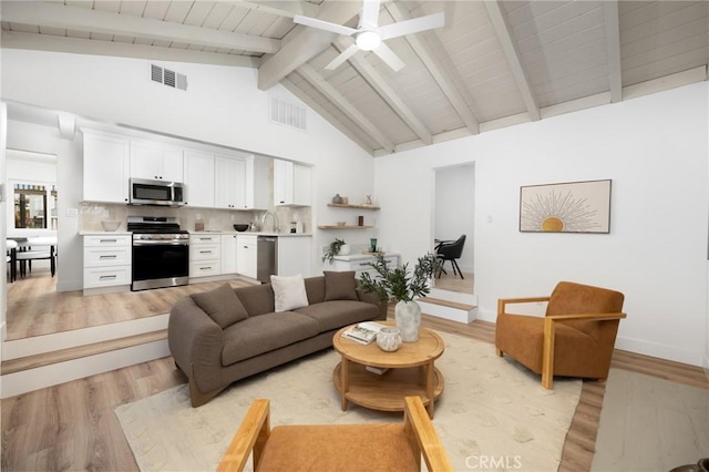 living room featuring ceiling fan, visible vents, beamed ceiling, and light wood finished floors