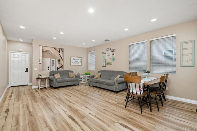 living room with visible vents, baseboards, wood finished floors, and stairway