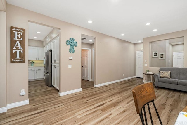 living room with recessed lighting, baseboards, and light wood-type flooring