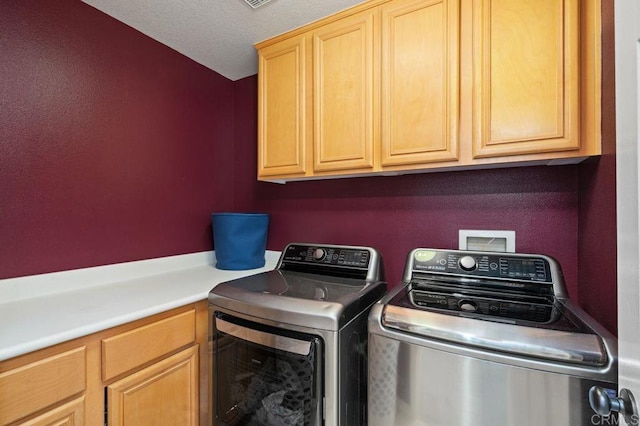 clothes washing area with cabinet space, visible vents, and washer and clothes dryer