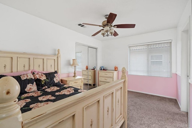 bedroom with a closet, ceiling fan, visible vents, and light carpet