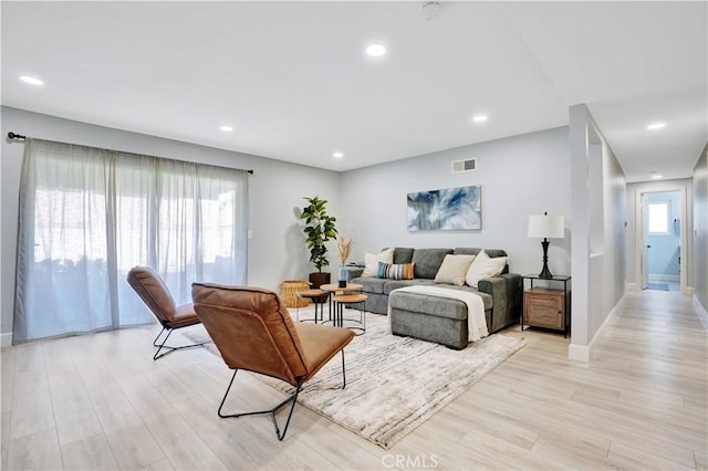 living area featuring light wood-type flooring, visible vents, and baseboards