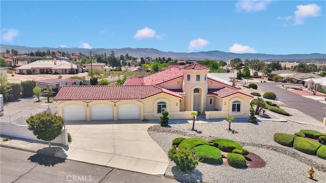 mediterranean / spanish-style house featuring an attached garage, a tiled roof, a mountain view, and concrete driveway