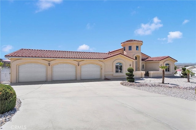 mediterranean / spanish home with a tile roof, concrete driveway, fence, a garage, and stucco siding