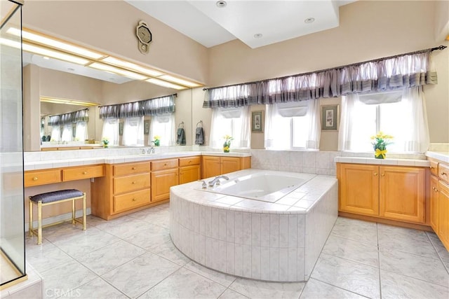 bathroom with a garden tub, marble finish floor, and vanity