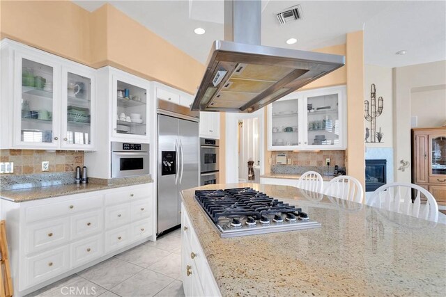 kitchen featuring tasteful backsplash, light stone counters, light tile patterned floors, appliances with stainless steel finishes, and visible vents