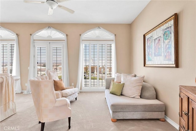 sitting room with ceiling fan, baseboards, and light carpet