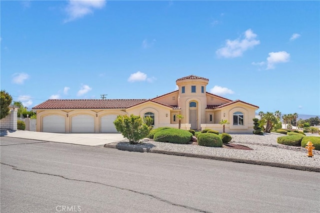 mediterranean / spanish home with an attached garage, a tile roof, concrete driveway, and stucco siding
