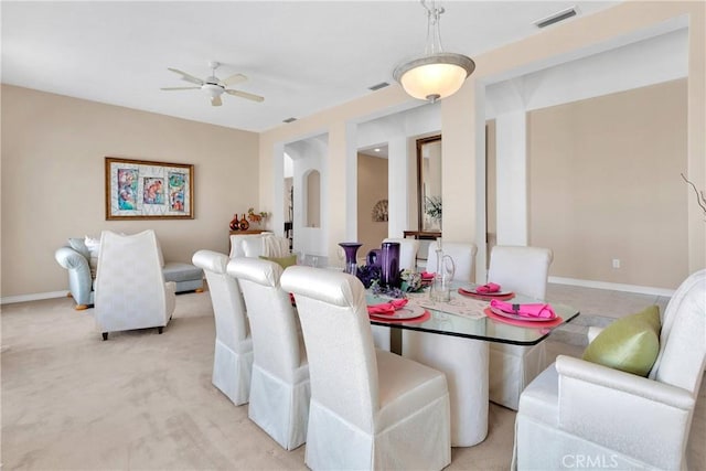 dining area featuring baseboards, a ceiling fan, visible vents, and light carpet