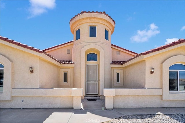 view of exterior entry with stucco siding and a tiled roof