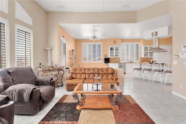 living room featuring ceiling fan, baseboards, and light tile patterned floors