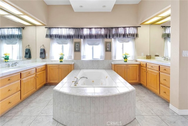 full bathroom with two vanities, a jetted tub, and a sink
