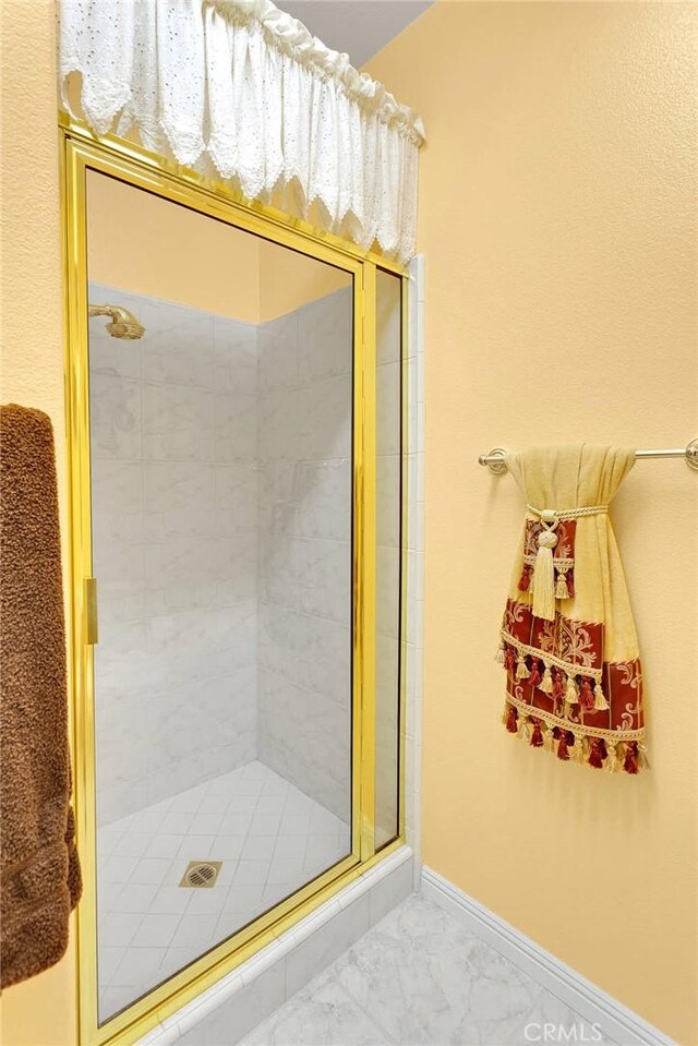 full bath with baseboards, marble finish floor, and a stall shower
