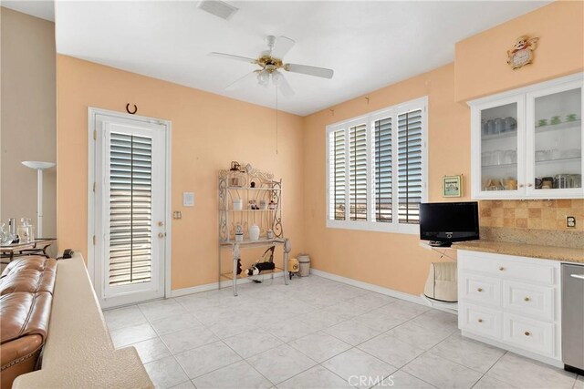 interior space featuring baseboards, a ceiling fan, visible vents, and light tile patterned floors