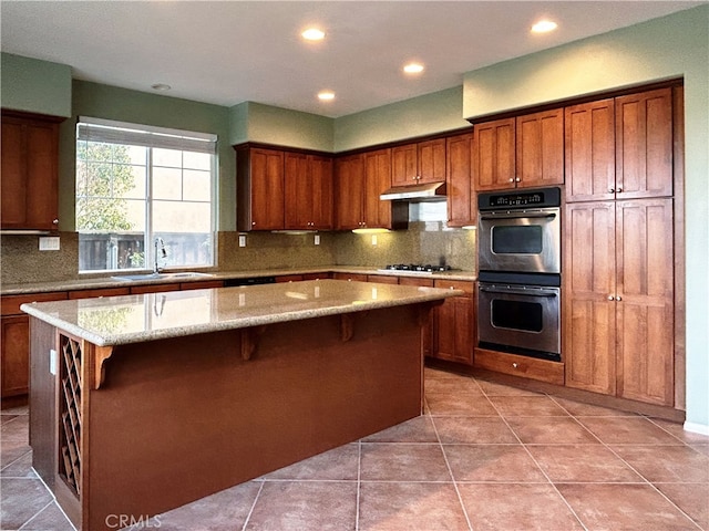 5743 Kendall Ct, Rancho Cucamonga, CA 91739 - kitchen featuring a sink, double oven, under cabinet range hood, a kitchen island, and tasteful backsplash