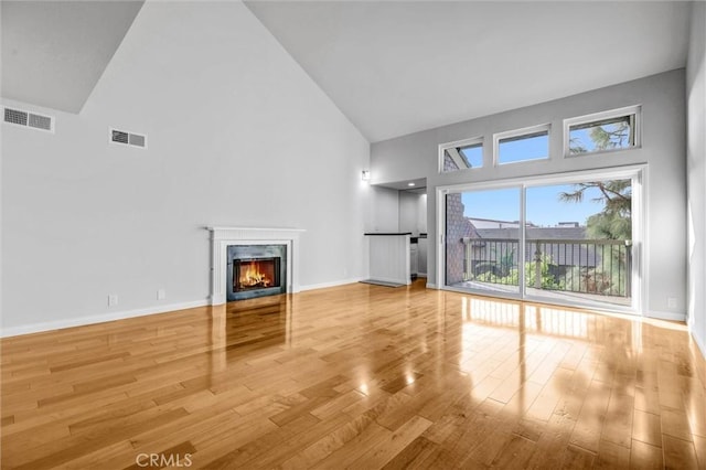 18324 Clark St Unit 315, Tarzana, CA 91356 - unfurnished living room featuring high vaulted ceiling, a high end fireplace, wood finished floors, and visible vents