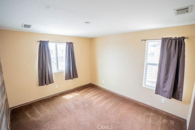 carpeted spare room featuring baseboards and visible vents