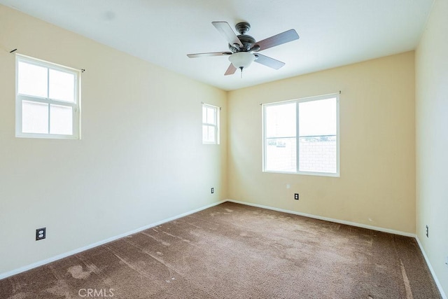 carpeted empty room with a ceiling fan and baseboards