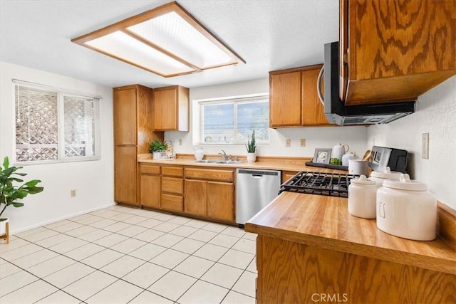 kitchen featuring butcher block countertops, stainless steel dishwasher, brown cabinets, and a sink