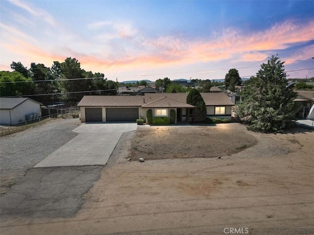 view of front of house with an attached garage, concrete driveway, and fence