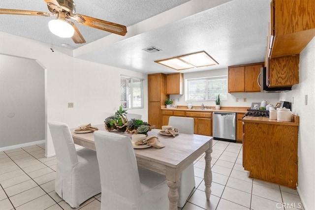 kitchen with brown cabinetry, a textured ceiling, and appliances with stainless steel finishes