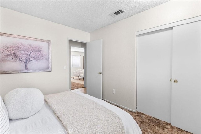 carpeted bedroom featuring a closet, visible vents, and a textured ceiling