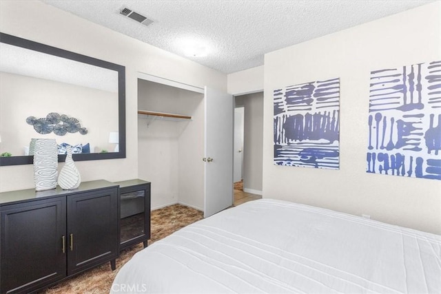 bedroom featuring a closet, visible vents, and a textured ceiling