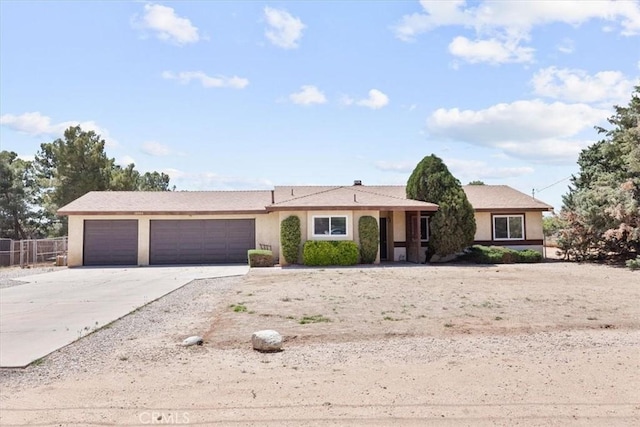 ranch-style home with stucco siding, an attached garage, concrete driveway, and fence