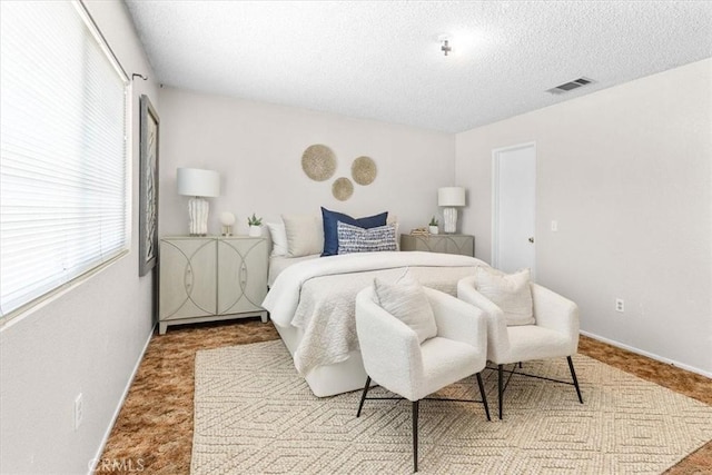 bedroom with carpet floors, multiple windows, visible vents, and a textured ceiling