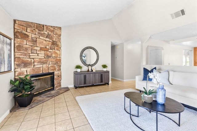 living room featuring a stone fireplace, tile patterned floors, baseboards, lofted ceiling, and visible vents