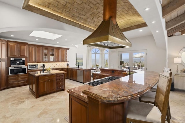 5955 Lake Vista Dr, Bonsall, CA 92003 - kitchen featuring appliances with stainless steel finishes, a sink, vaulted ceiling with skylight, brick ceiling, and a spacious island