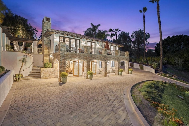 5955 Lake Vista Dr, Bonsall, CA 92003 - rear view of house with curved driveway, a balcony, stone siding, and stairs