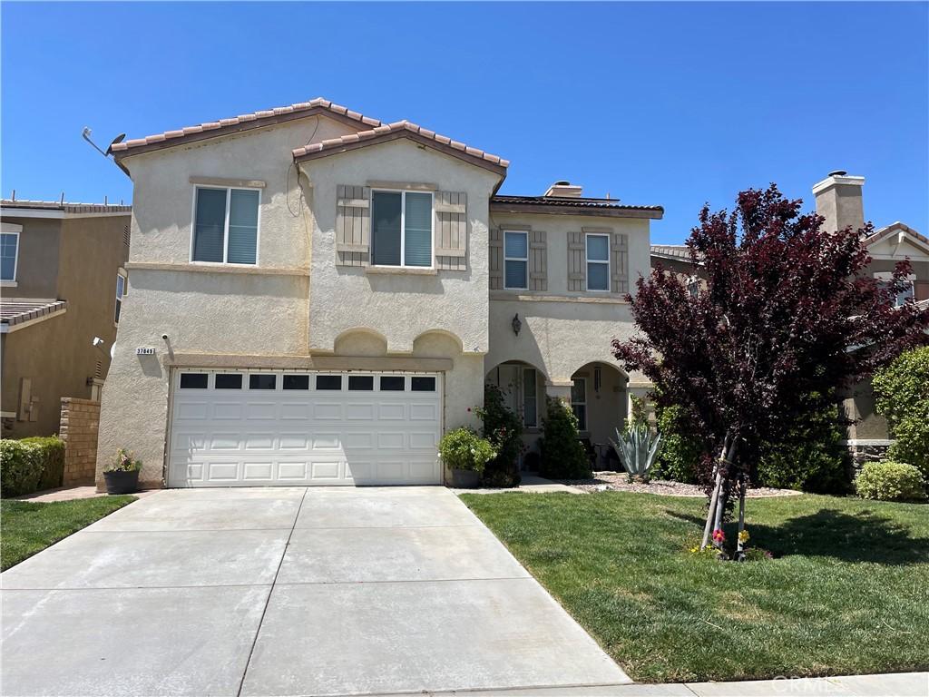 mediterranean / spanish home with a garage, stucco siding, concrete driveway, and a front yard
