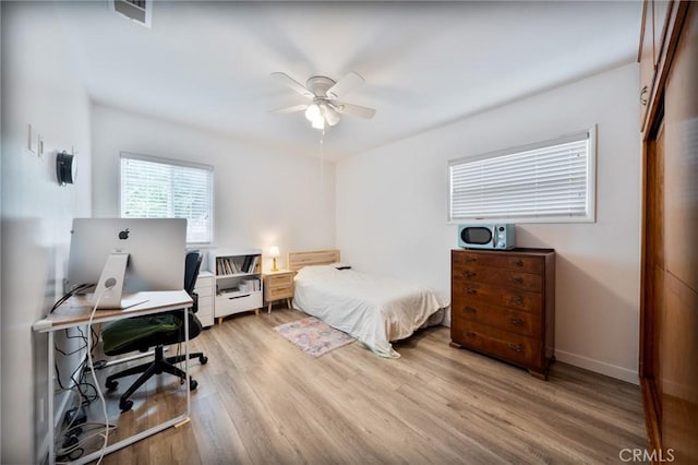 bedroom featuring baseboards, ceiling fan, wood finished floors, and visible vents