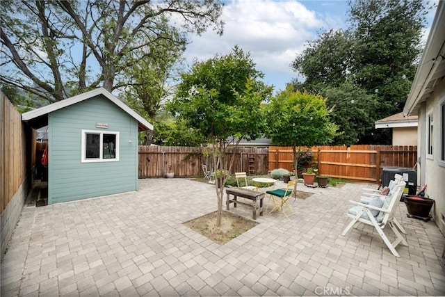 view of patio / terrace with an outdoor structure, a fenced backyard, and central air condition unit