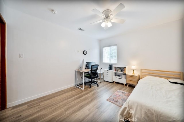bedroom with baseboards, a ceiling fan, wood finished floors, and visible vents