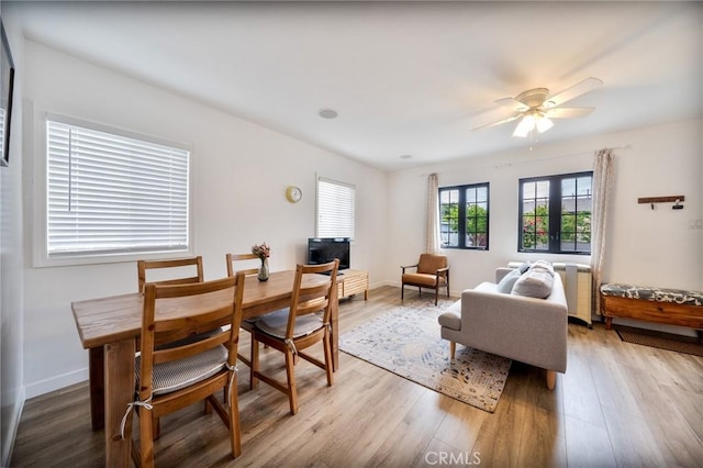 living area featuring a ceiling fan, baseboards, and wood finished floors