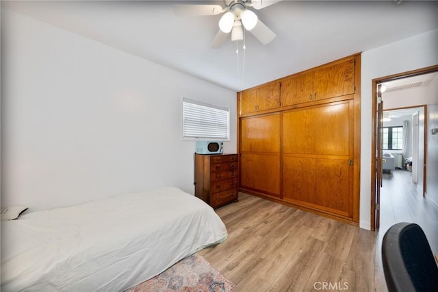 bedroom featuring light wood-style floors, ceiling fan, and a closet
