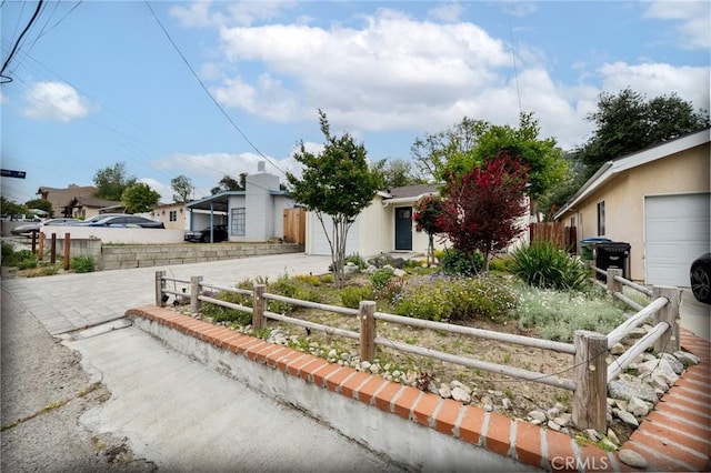 view of front of home with an attached garage, driveway, and fence private yard