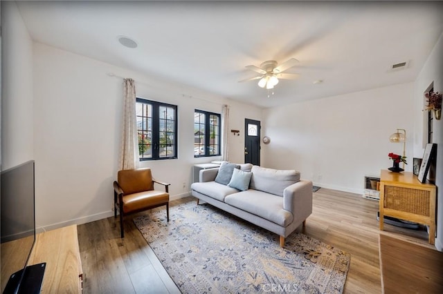 living area with baseboards, ceiling fan, visible vents, and wood finished floors