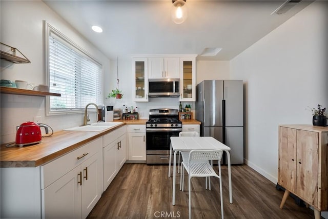 kitchen featuring visible vents, dark wood-style flooring, butcher block counters, a sink, and stainless steel appliances
