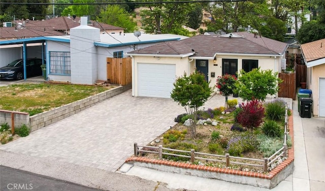 single story home featuring an attached garage, decorative driveway, fence, and stucco siding