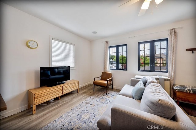 living room featuring baseboards, ceiling fan, and wood finished floors