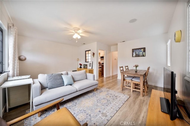 living room with a ceiling fan, baseboards, plenty of natural light, and light wood-style floors