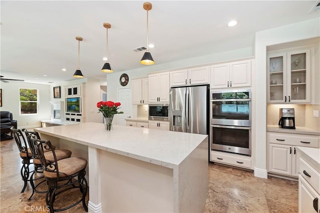1560 Vandagriff Way, Corona, CA 92883 - kitchen with stainless steel appliances, open floor plan, a kitchen island, a breakfast bar area, and white cabinets