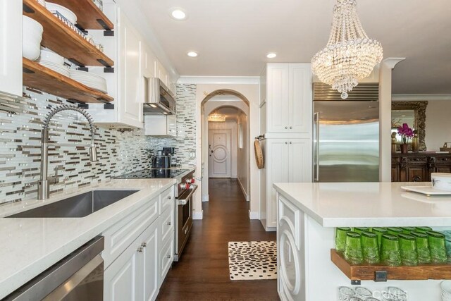 kitchen with high end appliances, open shelves, a sink, white cabinets, and ornamental molding