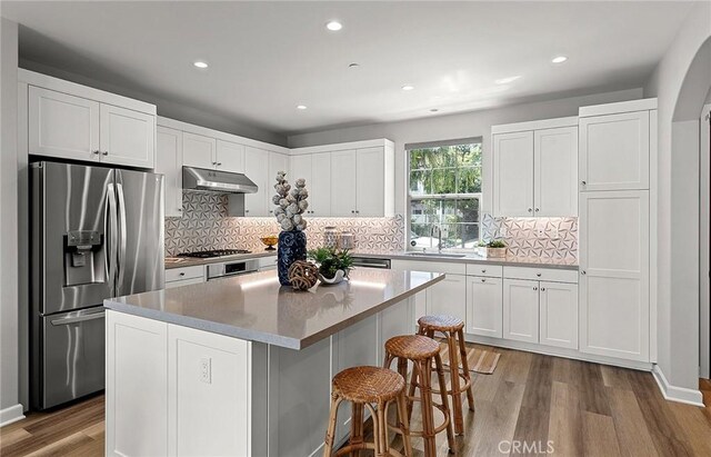 113 Soaring Eagle, Irvine, CA 92618 - kitchen featuring stainless steel appliances, under cabinet range hood, wood finished floors, recessed lighting, and a kitchen island
