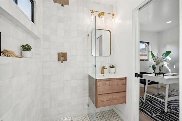 bathroom featuring a tile shower, a healthy amount of sunlight, and vanity
